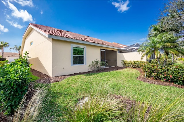 back of house featuring a lanai and a lawn