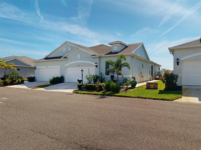 view of front of property featuring a garage, concrete driveway, a front lawn, and stucco siding