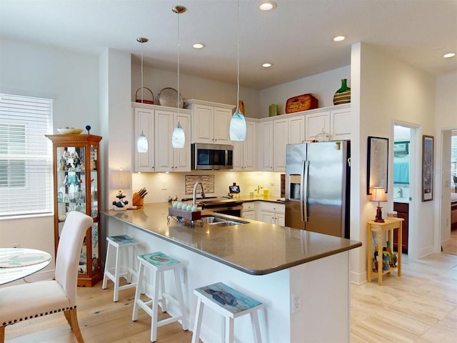 24313 Westgate Blvd, Punta Gorda, FL 33980 - kitchen featuring stainless steel appliances, a peninsula, a kitchen breakfast bar, tasteful backsplash, and a sink
