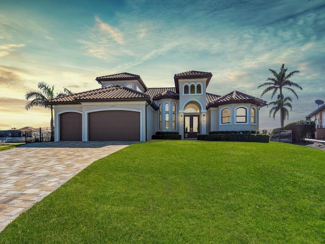 mediterranean / spanish-style house featuring a garage, a lawn, and french doors