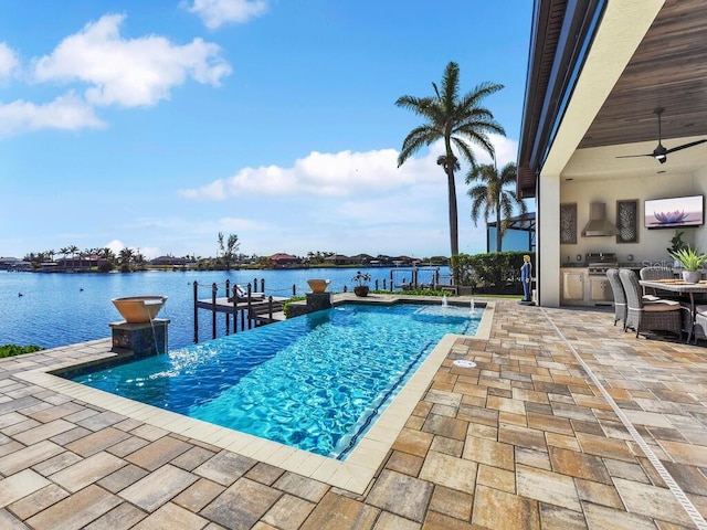 view of swimming pool with pool water feature, an outdoor kitchen, a water view, ceiling fan, and a patio