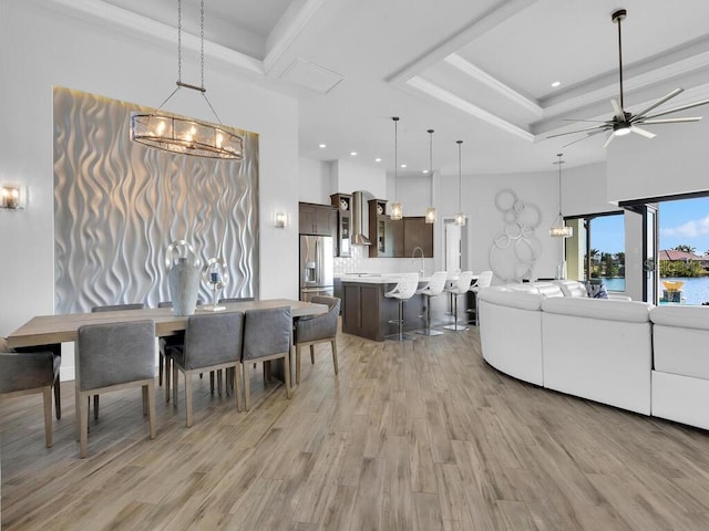 dining area featuring a tray ceiling, light hardwood / wood-style flooring, and a high ceiling