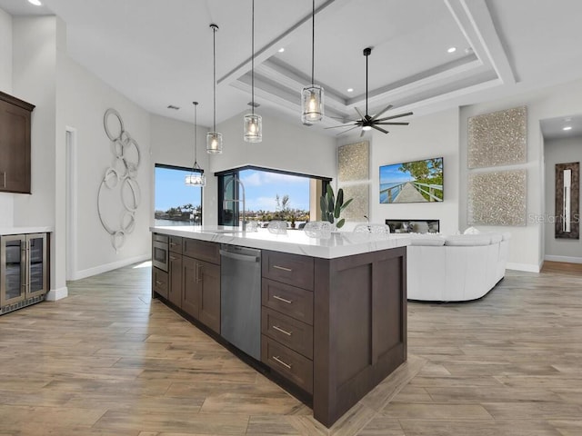 kitchen with pendant lighting, dark brown cabinets, stainless steel appliances, a kitchen island, and a raised ceiling