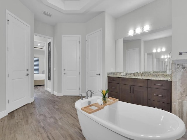 bathroom featuring wood-type flooring, vanity, and a washtub