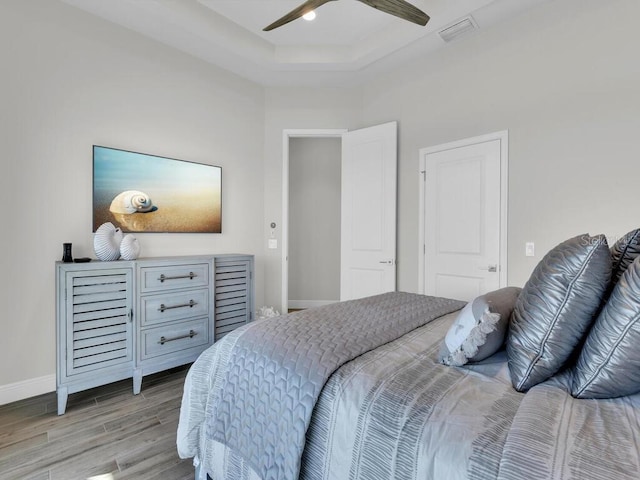 bedroom featuring light hardwood / wood-style floors, a raised ceiling, and ceiling fan