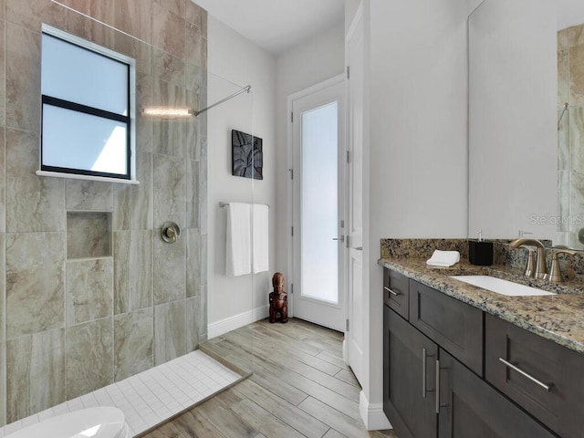 bathroom featuring vanity, hardwood / wood-style floors, and a tile shower