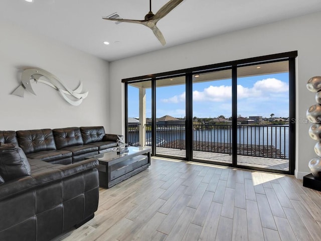 living room with a water view, ceiling fan, and light hardwood / wood-style flooring