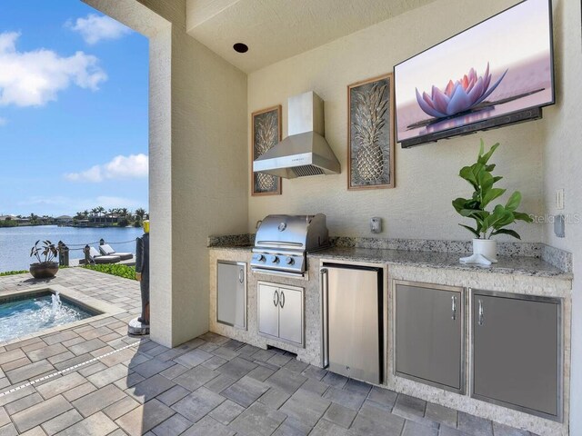 view of patio / terrace featuring exterior kitchen, a water view, area for grilling, and pool water feature