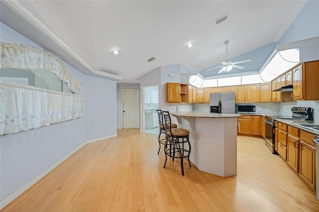 kitchen featuring light countertops, visible vents, appliances with stainless steel finishes, a kitchen island, and a kitchen breakfast bar