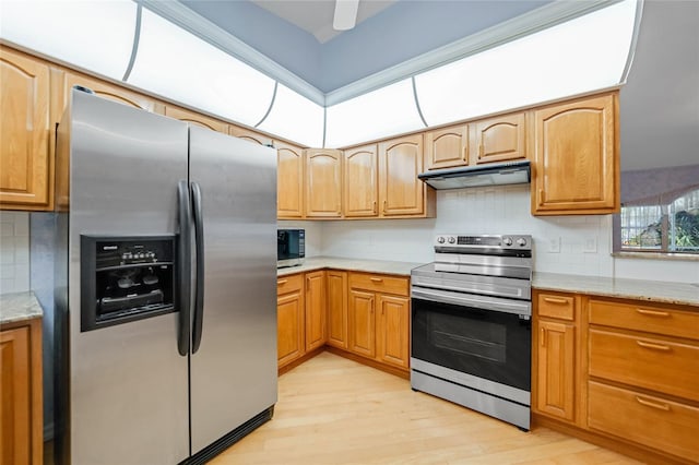 kitchen with stainless steel appliances, light wood-type flooring, decorative backsplash, and under cabinet range hood