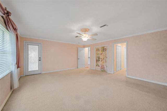 empty room with visible vents, ornamental molding, baseboards, and light colored carpet