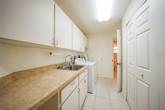 laundry area featuring light tile patterned flooring, independent washer and dryer, a sink, and cabinet space