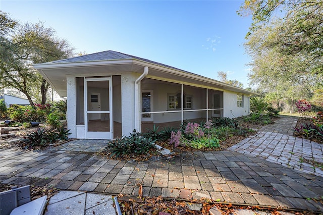 exterior space with roof with shingles, a patio, and stucco siding