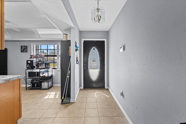 foyer entrance with light tile patterned floors and an inviting chandelier