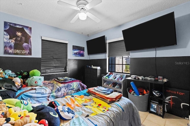 bedroom featuring ceiling fan, light tile patterned floors, and a textured ceiling