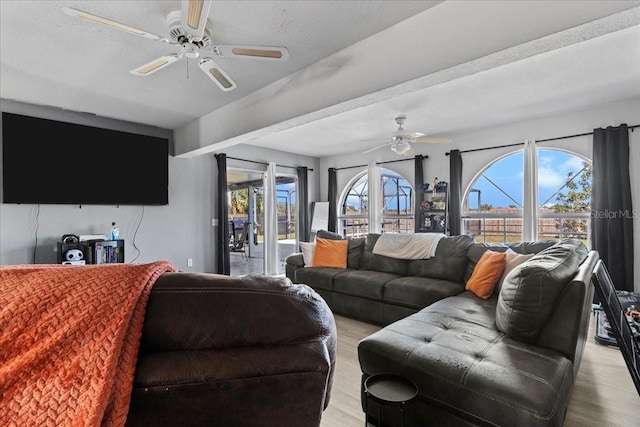 living room featuring light wood-type flooring, a textured ceiling, and ceiling fan