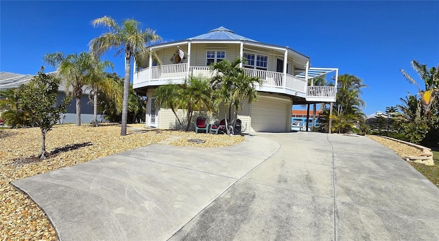 coastal home with an attached garage, metal roof, and concrete driveway