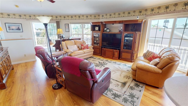 living area with light wood-style floors, baseboards, and a ceiling fan