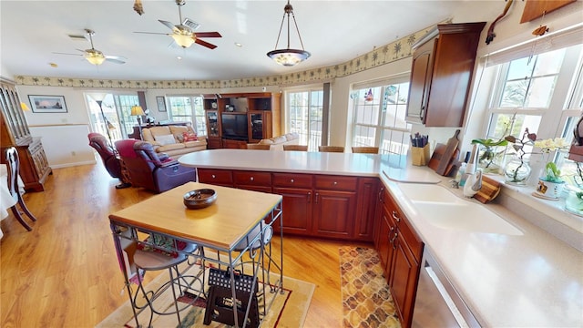 kitchen with light countertops, open floor plan, light wood-type flooring, dishwasher, and a peninsula