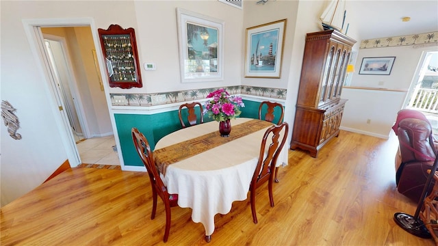 dining area with an AC wall unit, light wood finished floors, and baseboards