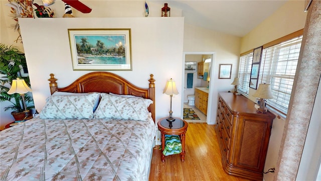 bedroom with vaulted ceiling, ensuite bath, and light wood finished floors