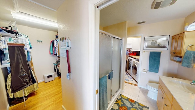 bathroom featuring visible vents, toilet, washing machine and clothes dryer, vanity, and a shower stall