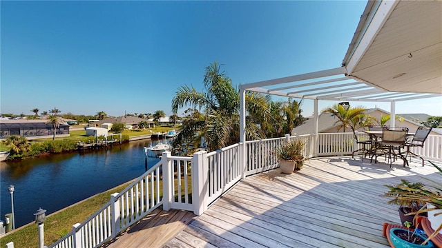 deck with outdoor dining space and a water view