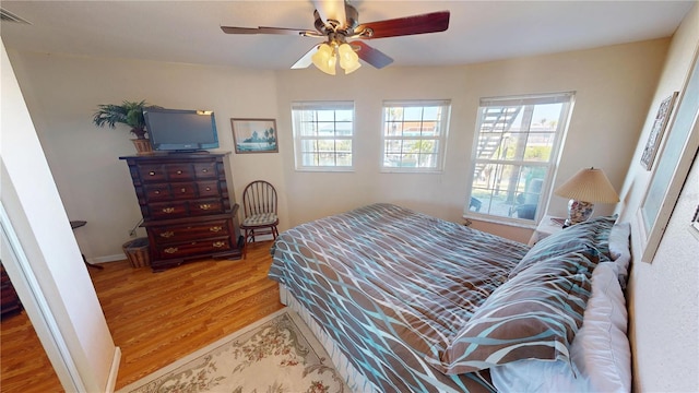 bedroom with light wood-style flooring, multiple windows, visible vents, and baseboards