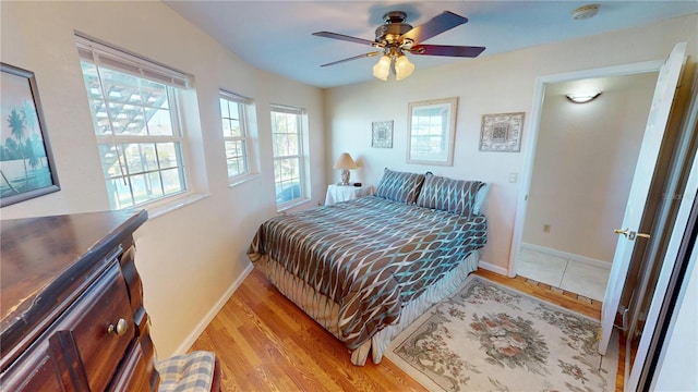 bedroom featuring a ceiling fan, baseboards, and wood finished floors