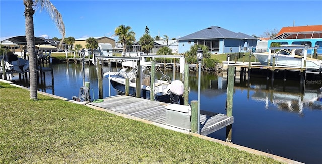 dock area with a water view, boat lift, a residential view, and a yard