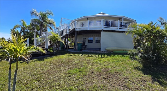 rear view of property featuring a deck, stairway, and a lawn