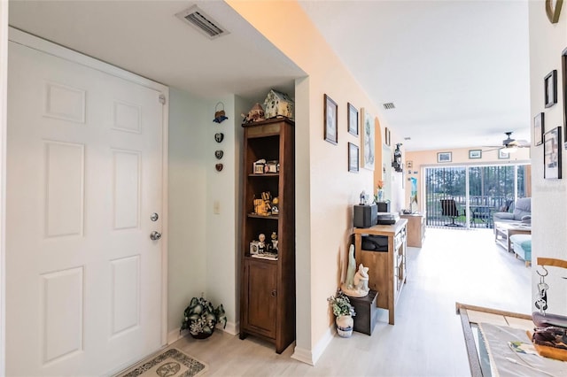 hallway featuring light wood-style floors, visible vents, and baseboards