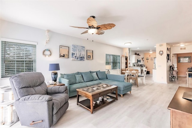 living room with light wood finished floors, visible vents, and a ceiling fan