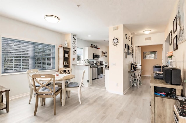 dining room featuring light wood-style flooring, visible vents, and baseboards