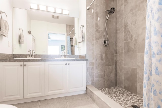 bathroom with double vanity, a shower stall, a sink, and tile patterned floors