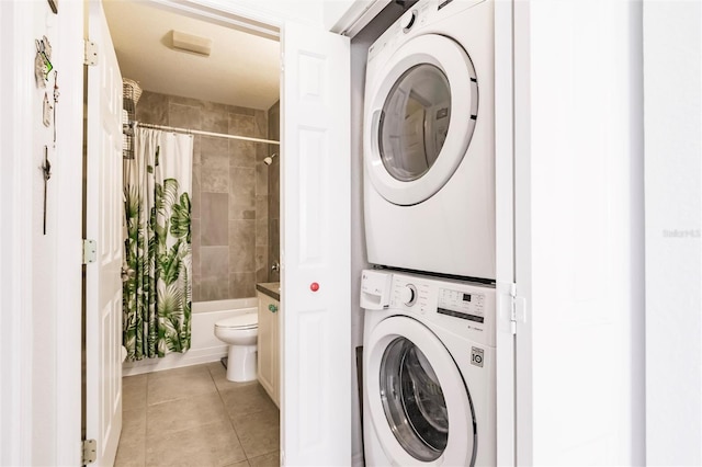 laundry area featuring light tile patterned floors, laundry area, and stacked washer / dryer