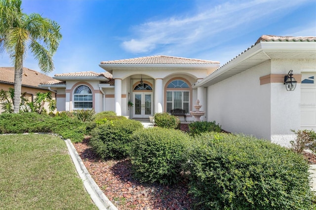 view of exterior entry featuring a garage, french doors, and a tile roof