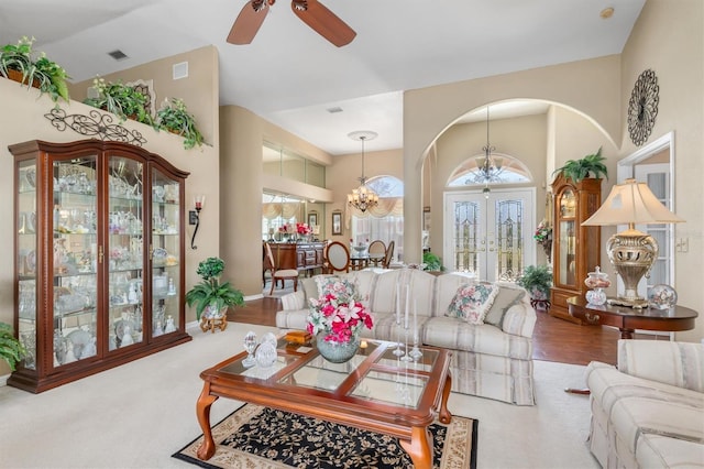 carpeted living area featuring a towering ceiling, visible vents, and french doors