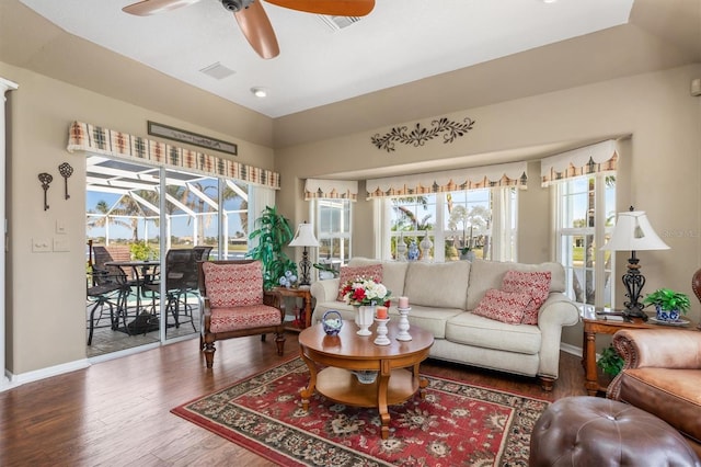 living room featuring a sunroom, a healthy amount of sunlight, visible vents, and wood finished floors