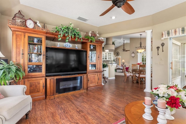 living area featuring lofted ceiling, visible vents, dark wood finished floors, and ornate columns