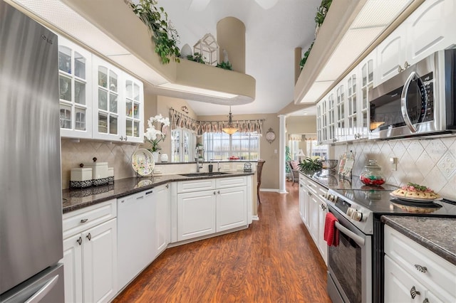 kitchen with a sink, white cabinetry, hanging light fixtures, appliances with stainless steel finishes, and glass insert cabinets