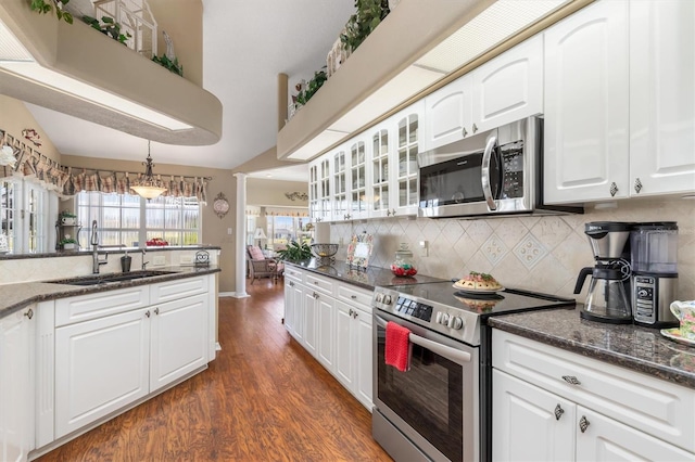 kitchen featuring stainless steel appliances, hanging light fixtures, glass insert cabinets, white cabinetry, and a sink