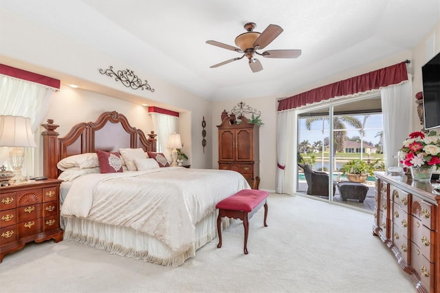 bedroom with light carpet, ceiling fan, a tray ceiling, and access to exterior