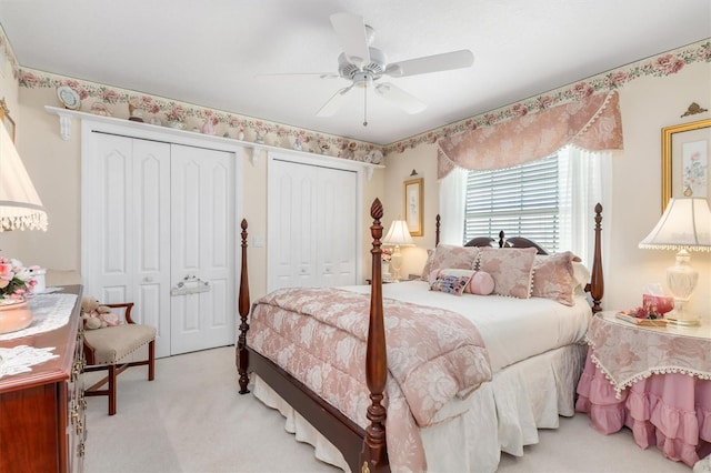 bedroom with a ceiling fan, light carpet, and two closets