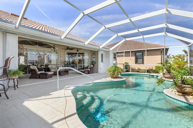 pool with glass enclosure, a patio area, and a ceiling fan