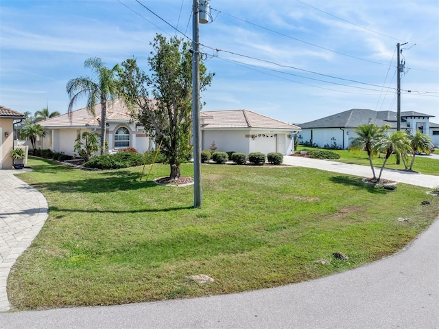 view of front of house featuring a garage, driveway, a tiled roof, and a front lawn