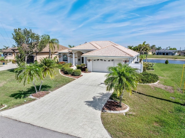 mediterranean / spanish home with an attached garage, a tiled roof, decorative driveway, and a front yard