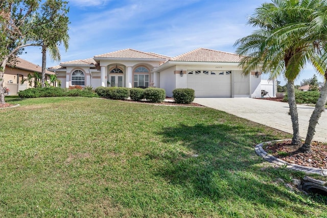 mediterranean / spanish home featuring a tiled roof, an attached garage, decorative driveway, a front lawn, and stucco siding