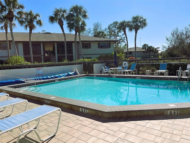 pool with a patio area and fence