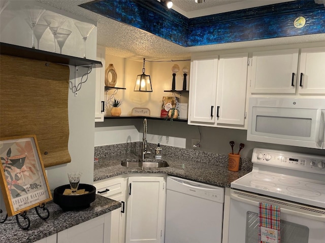 kitchen featuring white appliances, white cabinets, a sink, and a textured ceiling